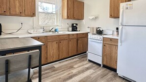 Una cocina compacta con armarios de madera, un refrigerador blanco, una estufa y un lavaplatos.