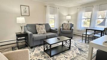 Relax in this inviting living room with a large sofa, armchair, and coffee table, perfect for unwinding.