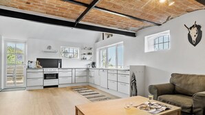 Una cocina moderna con armarios blancos, una estufa negra y una ventana con vistas a un jardín.