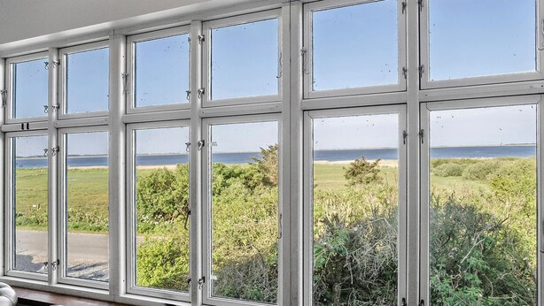 Una habitación con un ventanal grande que da a un área verde y un cuerpo de agua.
