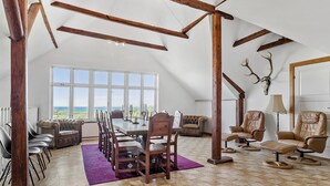 Un loft amplio con techo alto, vigas de madera a la vista, zona de comedor con vistas y mobiliario de cuero.