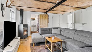 Una sala de estar acogedora con chimenea, un sofá gris, una mesa de centro de madera y una televisión.
