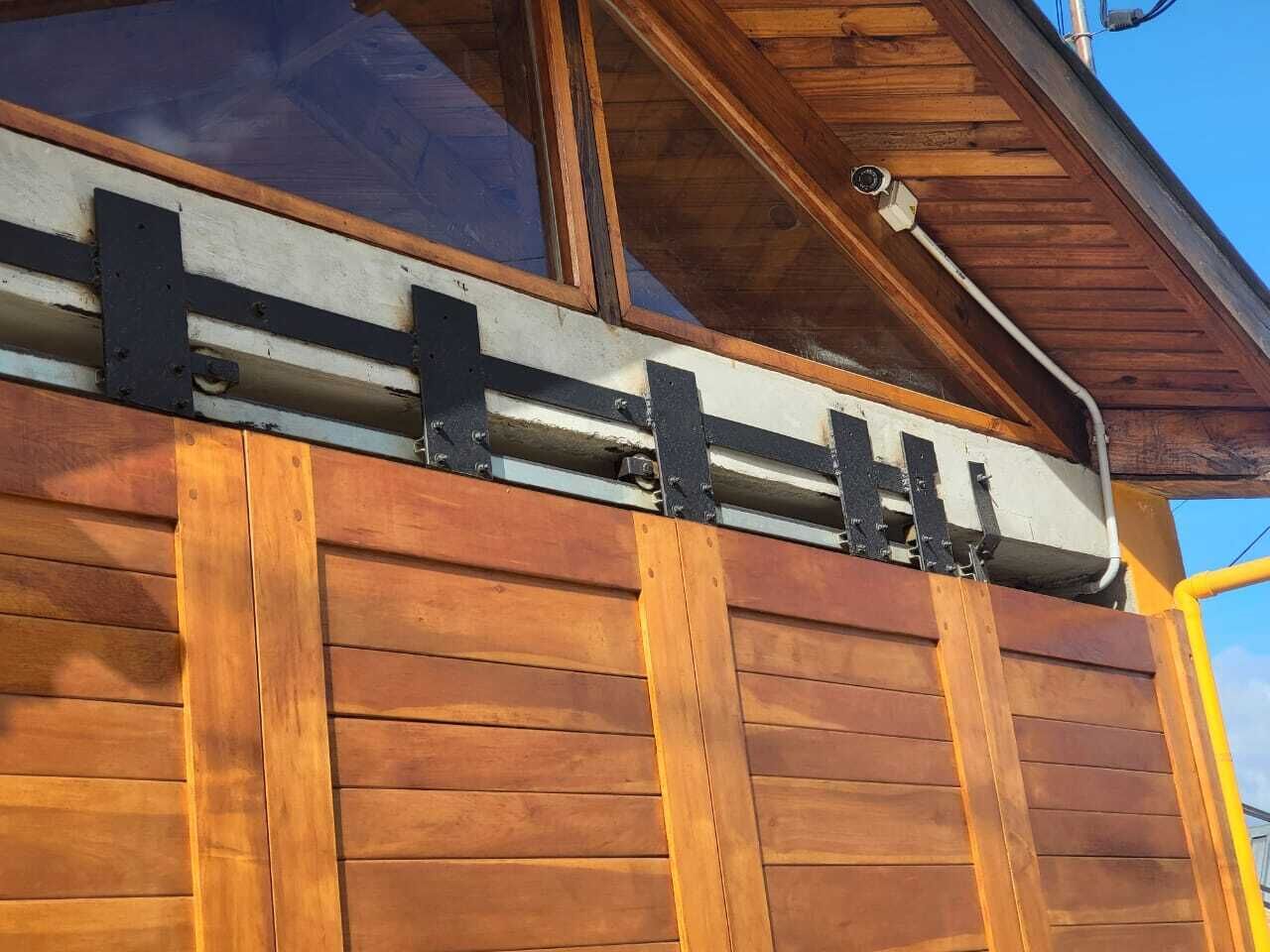 A wooden exterior wall with a window and a metal railing.