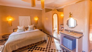 A hotel room with a bed, bedside tables, a mirror, and a bathroom with a sink and toilet. - Riad Villa Amood (Taouz)
