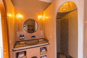 Casa de banho com um espelho grande, duas luzes de parede, uma pia e zona de duche.