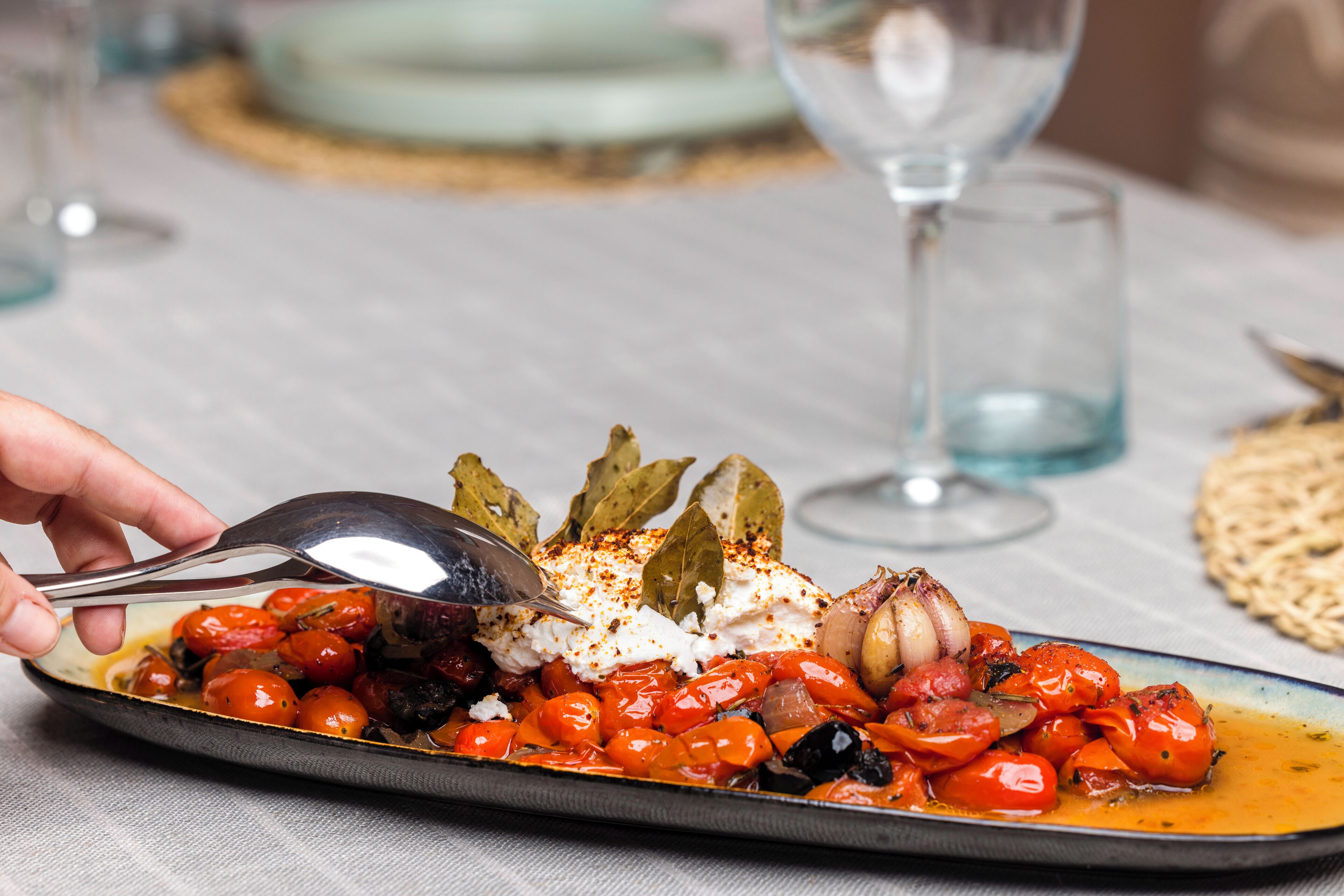 Une assiette de nourriture, une cuillère, un verre d’eau et un verre de vin sont posés sur une table.