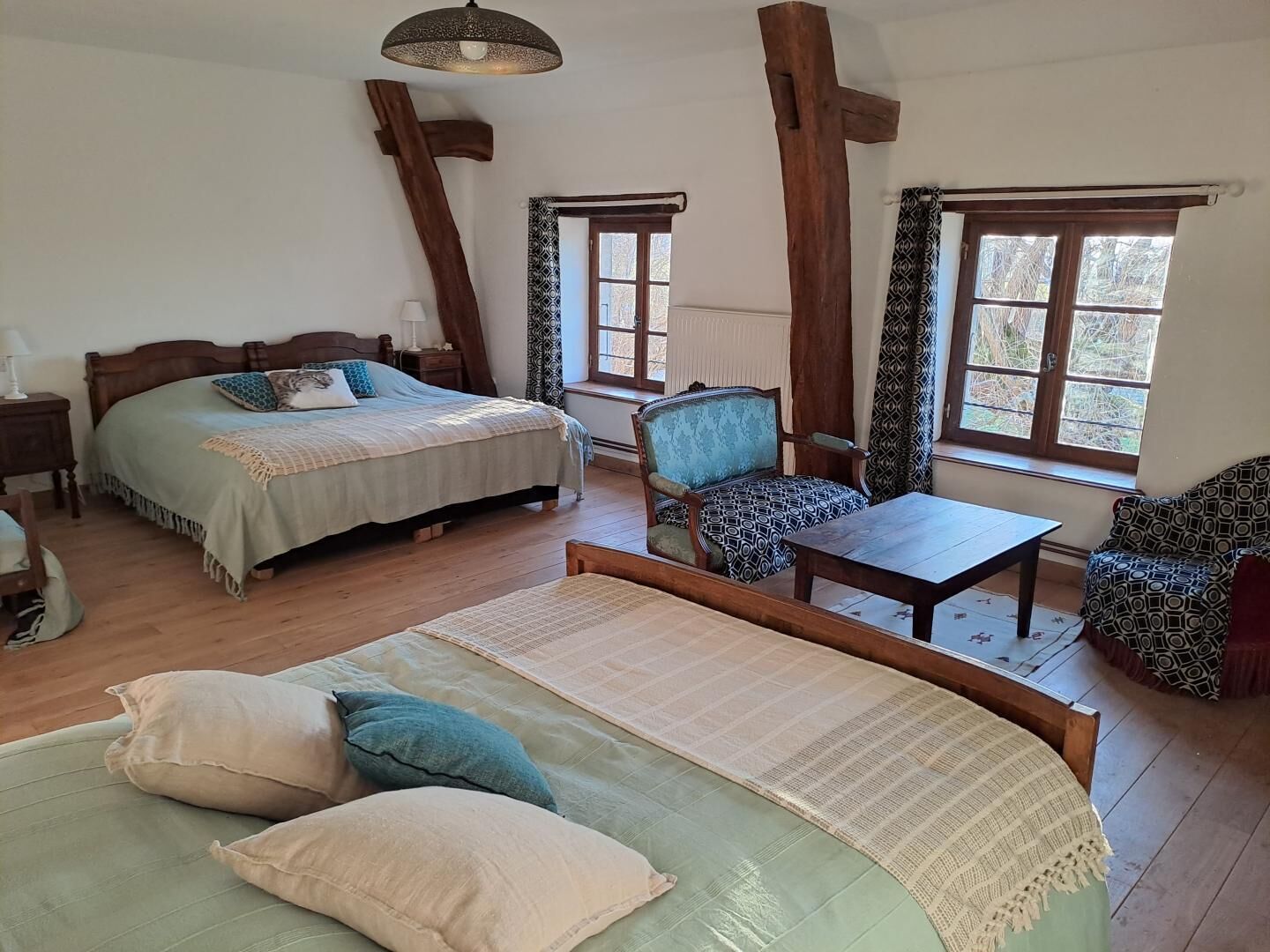 Een kamer met een bed, een stoel, een tafel en grote ramen.