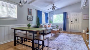 Ein geräumiges Wohnzimmer mit Holztisch, einer Couch und einem Deckenventilator.