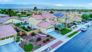 A residential area with houses featuring red-tiled roofs, a swimming pool, and a well-maintained lawn. - Coachella Escape. Brand New Luxury home in gated community. (Indio)