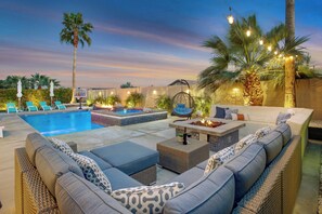 A pool area with lounge chairs, a hot tub, and a seating area with cushions and a hanging chair. - Coachella Escape. Brand New Luxury home in gated community. (Indio)