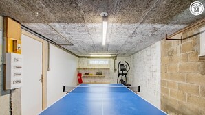 Une pièce équipée d’une table de ping-pong, d’un extincteur et de panneaux électriques.