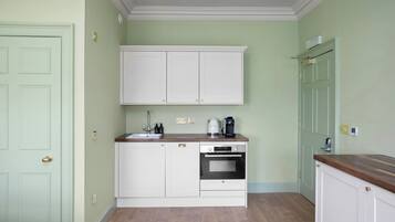Una cocina con gabinetes blancos, una encimera de madera y un horno empotrado.