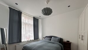 A bedroom with a bed, a radiator, a window with curtains, a ceiling light, and a wardrobe. - Enjoy your stay in a cosy corner in Rotterdam (Rotterdam)