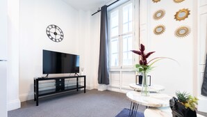A modern living room with a flat-screen TV, a glass cabinet, a round marble table, and decorative wall mirrors. - 30% OFF Monthly | Family & Work Stays - Contact us for better rates! (Woodhouse)