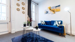 A living room with a blue sofa, decorative wall art, and a floor lamp. - 30% OFF Monthly | Family & Work Stays - Contact us for better rates! (Woodhouse)