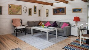 A cozy living room with a wooden ceiling, a grey sofa, a white coffee table, and a colorful striped rug. - 3 bedroom nice home in Sölvesborg (Sölvesborg)