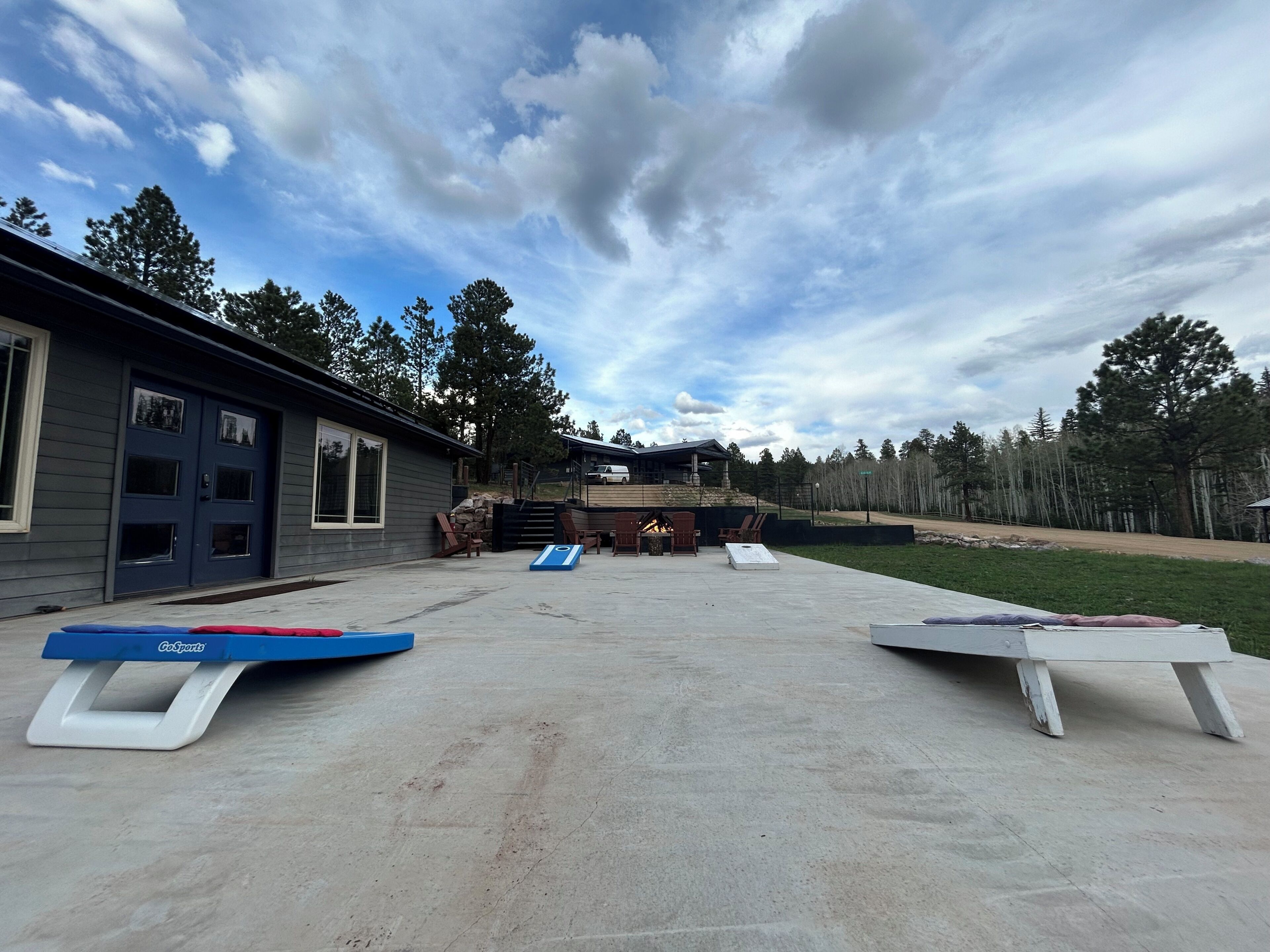 A backyard with a concrete patio, two GoSports jump boxes, a fire pit, and a house with a garage.