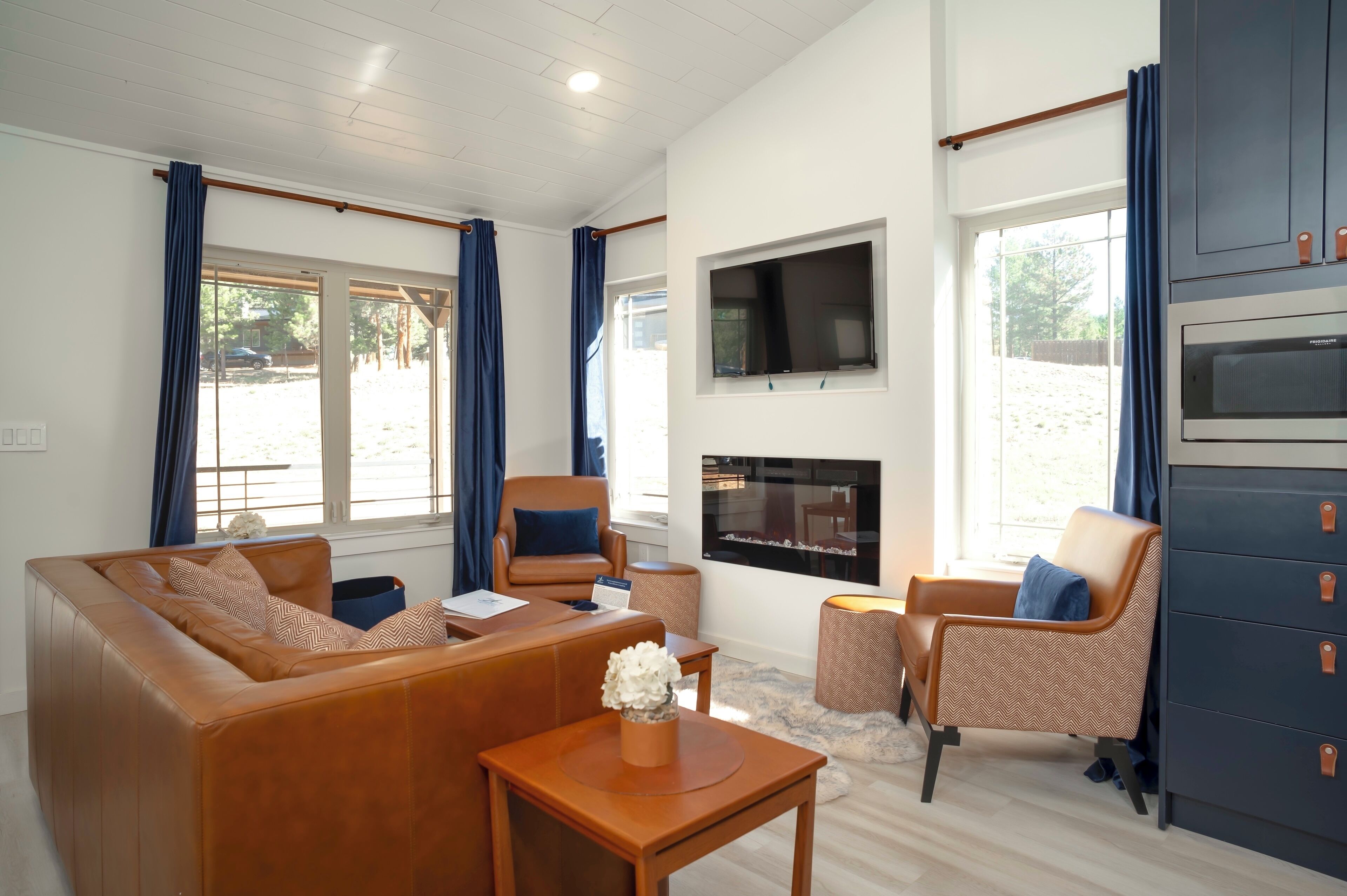 A living room with a sofa, chairs, a TV, a fireplace, and a large window.