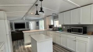 Una cocina moderna con armarios blancos, una isla central y un microondas.