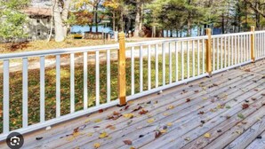 Una terraza de madera con barandal blanco, rodeada de  árboles con follaje otoñal.