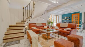 Un vaste espace de vie comprenant un escalier, des canapés en cuir, une table basse et un coin repas agrémenté d’un mur d’accent bleu.