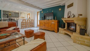 Un vaste salon doté d’une cheminée, d’un téléviseur et d’une cuisine à l’arrière-plan.