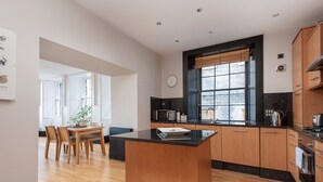A modern kitchen with wooden cabinets, a black countertop island, and a large window with a view.