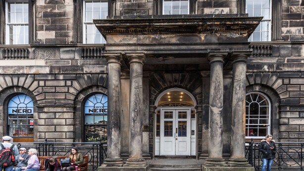 A historic building with a grand entrance featuring columns and a large arched doorway.