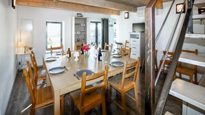 A dining area with a wooden table set for four, surrounded by wooden chairs. There is a white cabinet with glassware and a television on a stand. - Nice home in La Garde Adhémar (La Garde Adhémar)