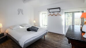 A bedroom with a bed, bedside lamps, a wooden dresser, and a window with curtains. - Nice home in La Garde Adhémar (La Garde Adhémar)