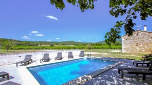 A rectangular swimming pool with a clear blue water surface, surrounded by lounge chairs and a stone wall. - Nice home in La Garde Adhémar (La Garde Adhémar)