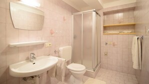 A bathroom with a sink, toilet, shower, and towel rack.