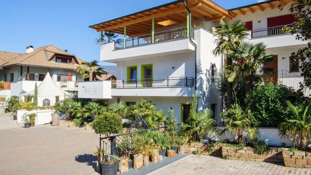 A multi-story building with balconies, a covered outdoor area, and a courtyard with potted plants.