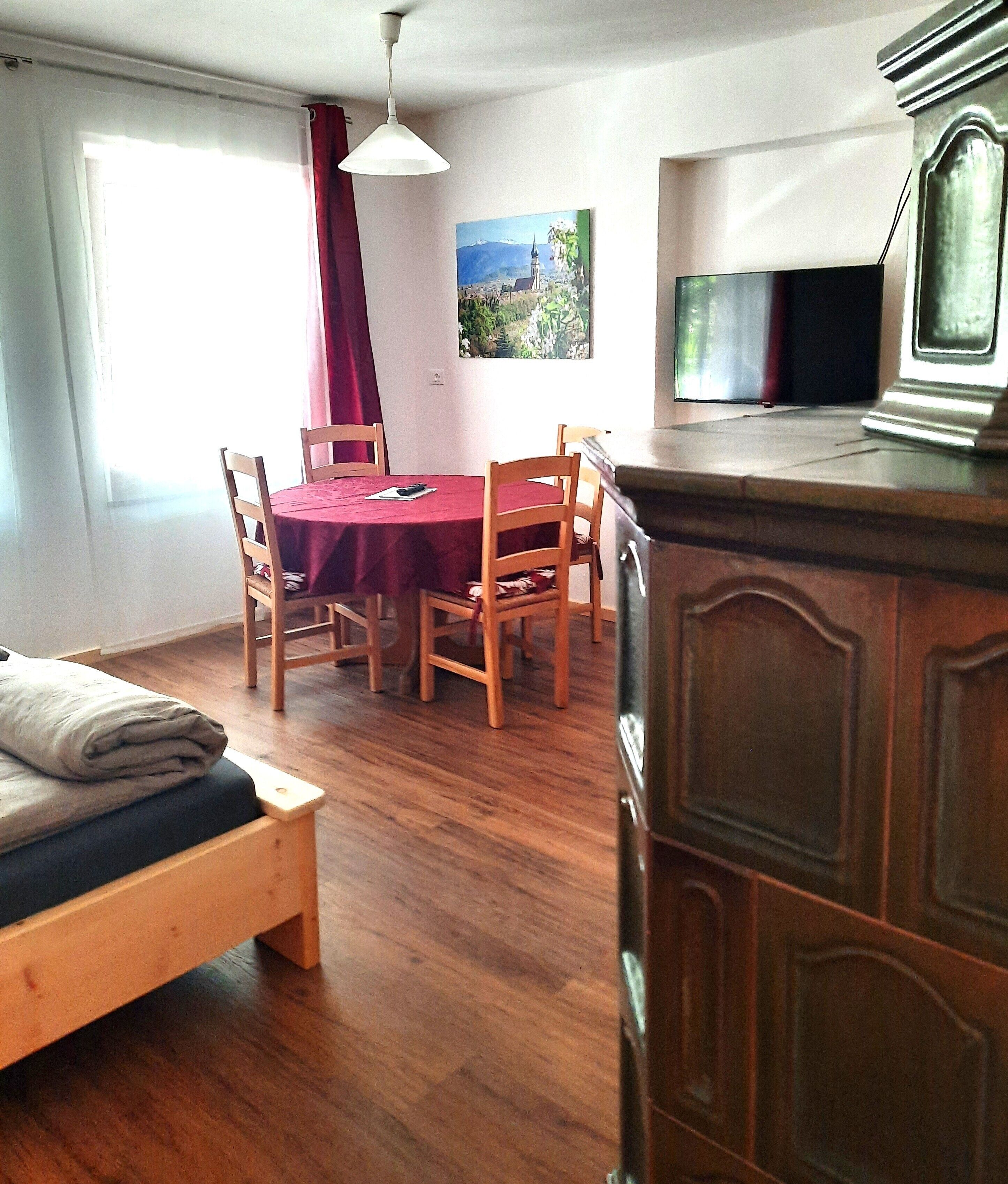 Une pièce comprenant un lit, une table à manger avec des chaises, un téléviseur et un tableau accroché au mur.
