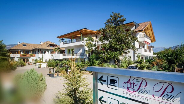 Une enseigne pour Peter Paul Konditorei & Café, avec des flèches indiquant la direction et une icône d’application.
