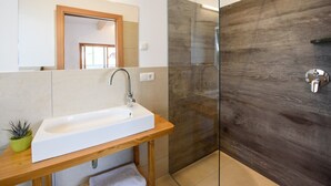 Une salle de bain moderne avec un meuble-lavabo en bois, un lavabo blanc, une cabine de douche en verre et un miroir au-dessus du lavabo.