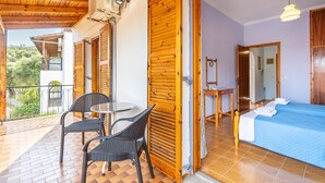 Habitació amb llit, taula, cadires, un balcó amb barana i sostre de fusta.
