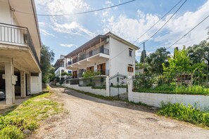 Un bâtiment à deux étages doté d’un balcon, d’une allée en gravier et d’une clôture.