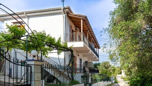 Edifici de dues plantes amb un balcó, una escala i una entrada tancada per una reixa.