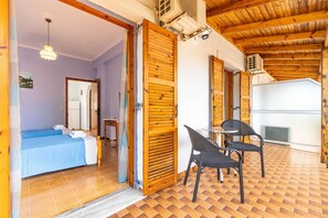Une pièce comprenant un lit, une chaise, une table et une porte ouverte donnant sur une autre pièce.