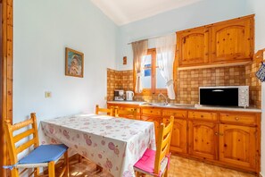 Une cuisine avec des meubles de rangement en bois, un four à micro-ondes et une table avec des chaises.