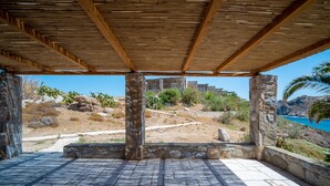 A covered outdoor area with stone pillars, a tiled floor, and a view of a mountainous landscape with a body of water.