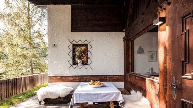 A rustic outdoor seating area with a table and benches, a wooden door, and a wall-mounted picture frame. - Chalet 'Am Reschensee' with Lake View, Private Terrace and Private Garden (Resia)