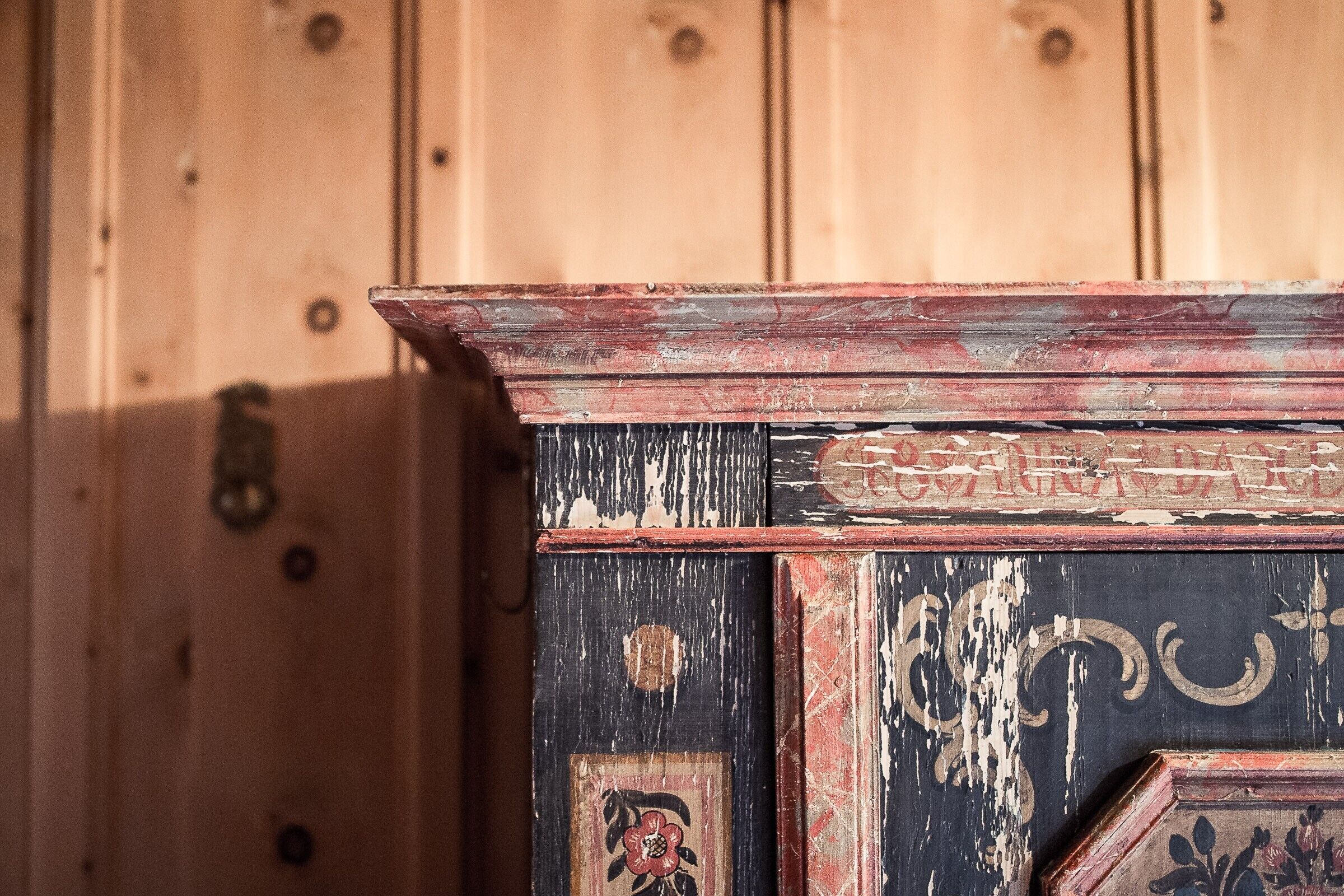 A wooden cabinet with a distressed finish and decorative elements.