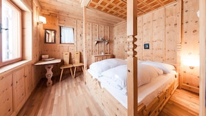 A wooden cabin room with a bed, a small table, a chair, and a mirror. - Chalet 'Am Reschensee' with Lake View, Private Terrace and Private Garden (Resia)