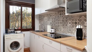 A compact kitchen with a washing machine, microwave, and coffee maker. - "La Azomadilla" Apartment with Shared Terrace and Wi-Fi (Totalán)