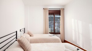 A hotel room with two beds, a window with curtains, and a view of buildings outside. - "La Azomadilla" Apartment with Shared Terrace and Wi-Fi (Totalán)