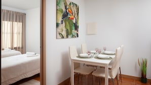 A hotel room with a dining area, a bed, and a painting of toucans. - "La Azomadilla" Apartment with Shared Terrace and Wi-Fi (Totalán)