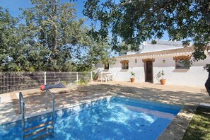 A swimming pool with a tiled deck, a white building with arched doorways, and potted plants. - Villa 'Casa da Maria Teresa V5' with Private Pool, Wi-Fi, and Air Conditioning (Santa Catarina da Fonte do Bispo)