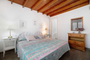 Ein Schlafzimmer mit einem Bett, Nachttischen, einem Schminktisch und einer Decke mit Holzbalken.